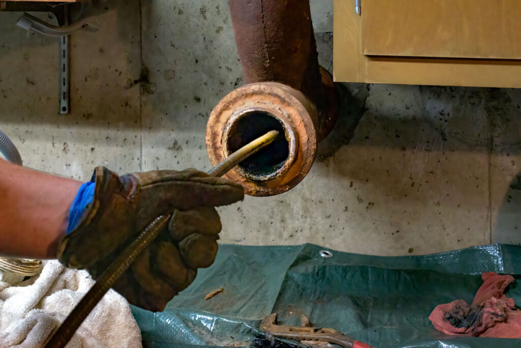 Hands of a plumber as he runs a camera scope and cleaning machin